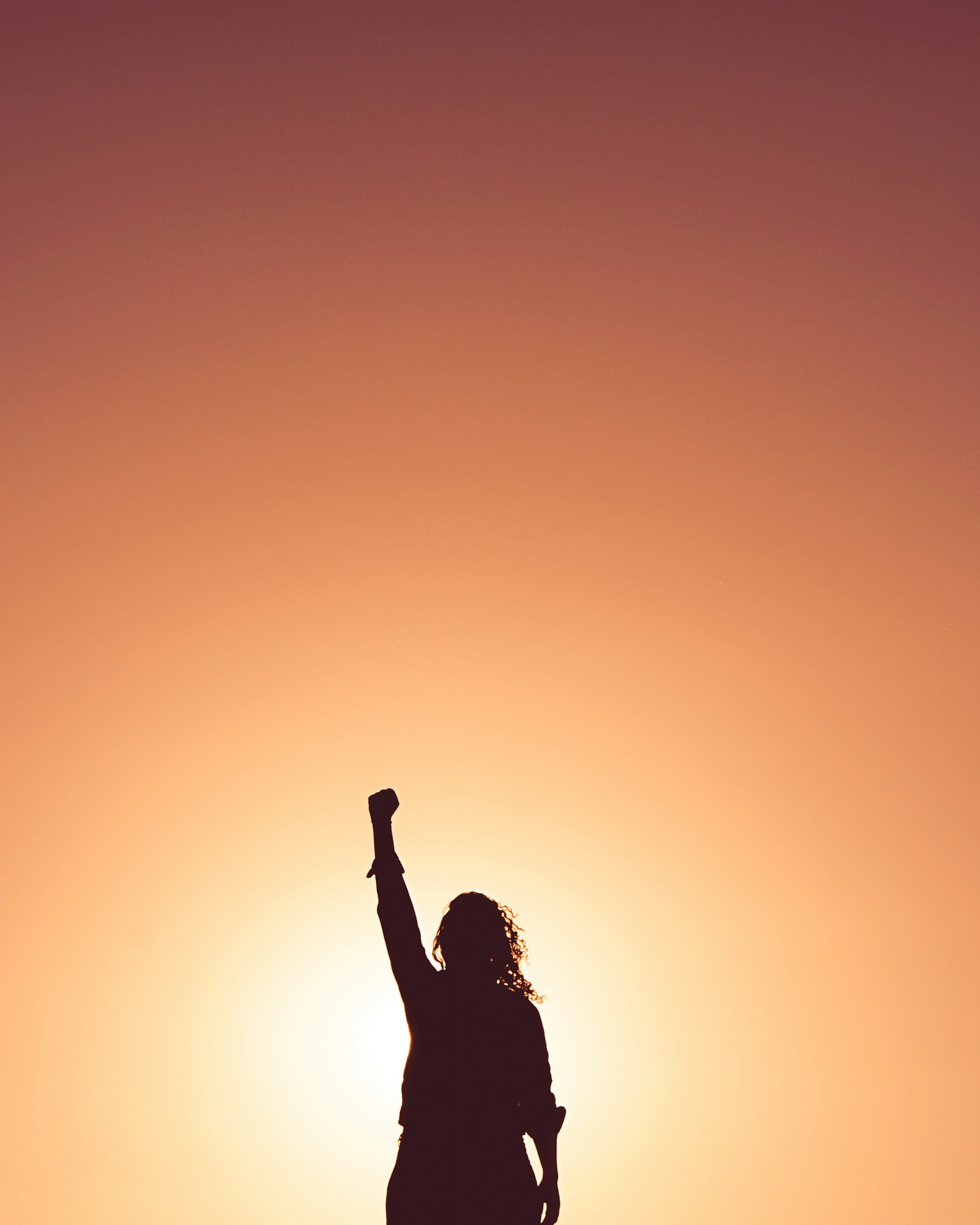 Mujer con mano levantada en el atardecer